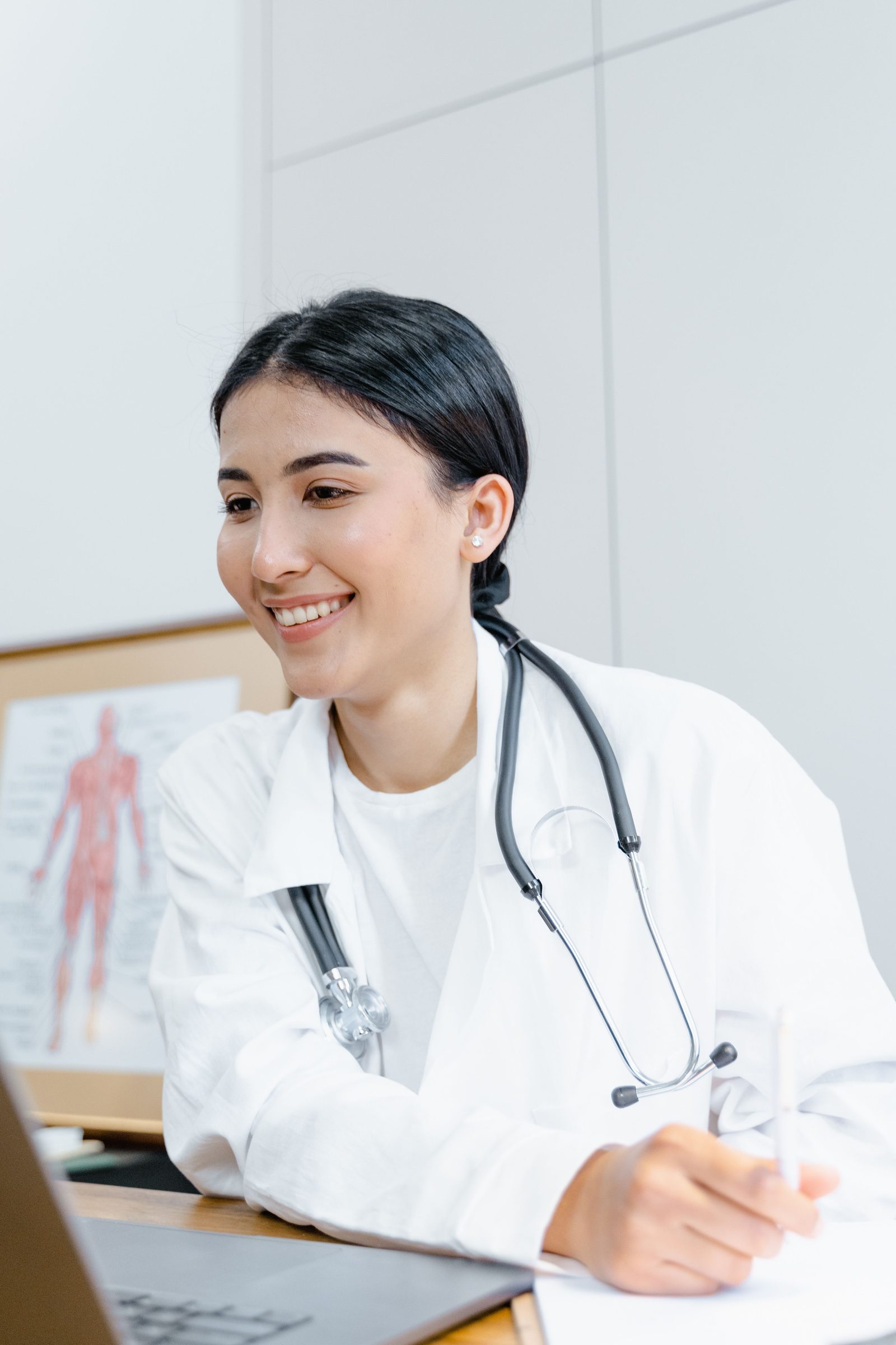 Doctora sonriendo junto a su escritorio en la consulta
